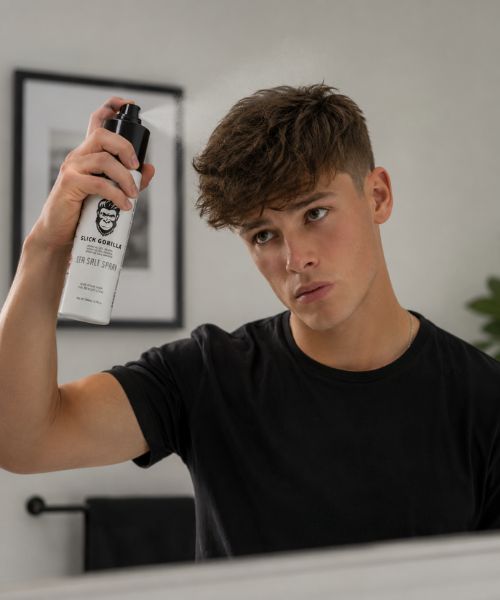 Man adding texture and volume with Slick Gorilla Sea Salt Spray before styling his hair.