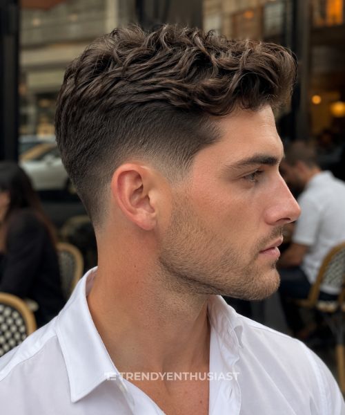 Classic low taper fade haircut on a man with textured dark hair in a close-up side profile.