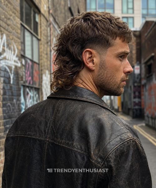 Modern taper fade mullet on rugged man with textured wavy hair and leather jacket